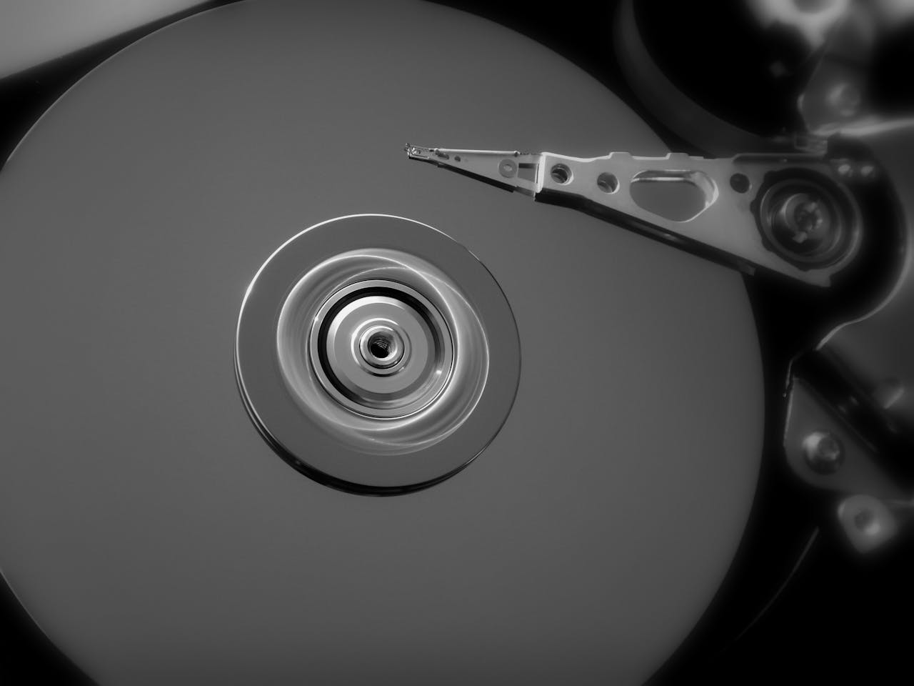 Detailed black and white close-up of an open hard drive, showcasing its mechanical components.